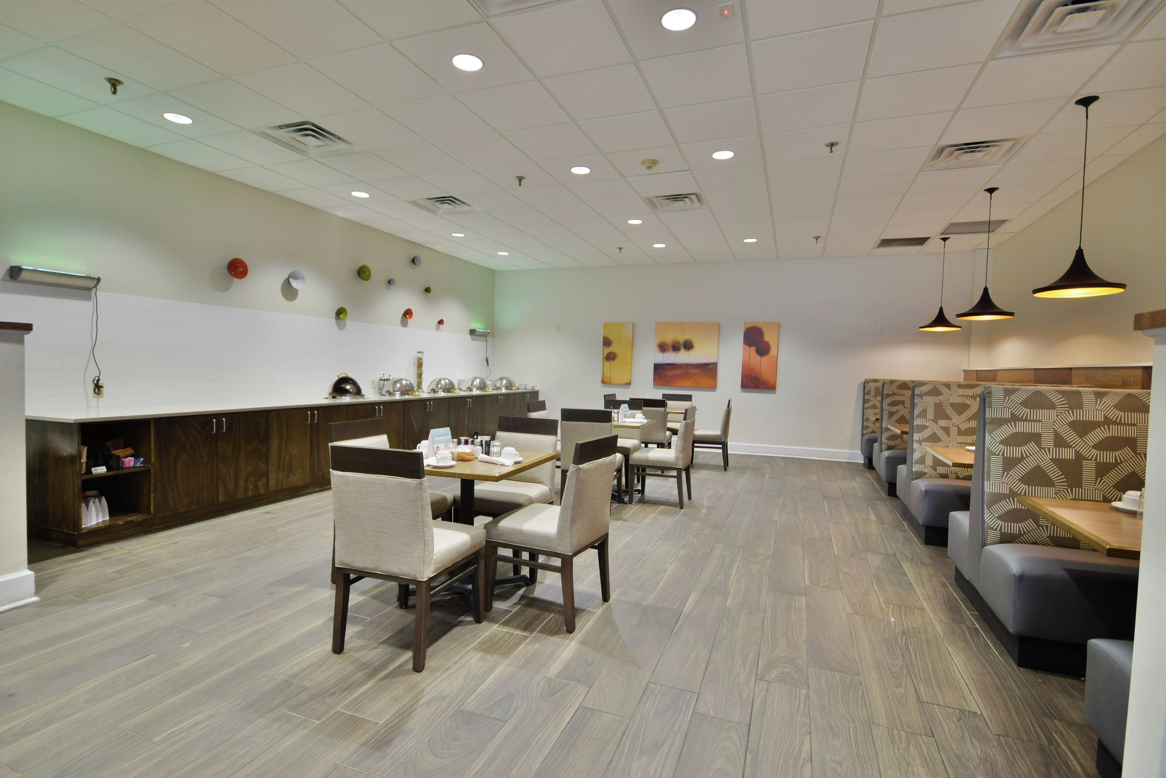 Un interior de restaurante moderno con suelo de madera, mesas y cabinas.