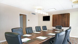 A conference room with a long table, six chairs, a flat-screen TV, and a wooden panel on the wall. - Holiday Inn Downtown Memphis by IHG (Memphis)