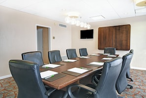 A conference room with a long table, six chairs, a flat-screen TV, and a wooden panel on the wall. - Holiday Inn Downtown Memphis by IHG (Memphis)