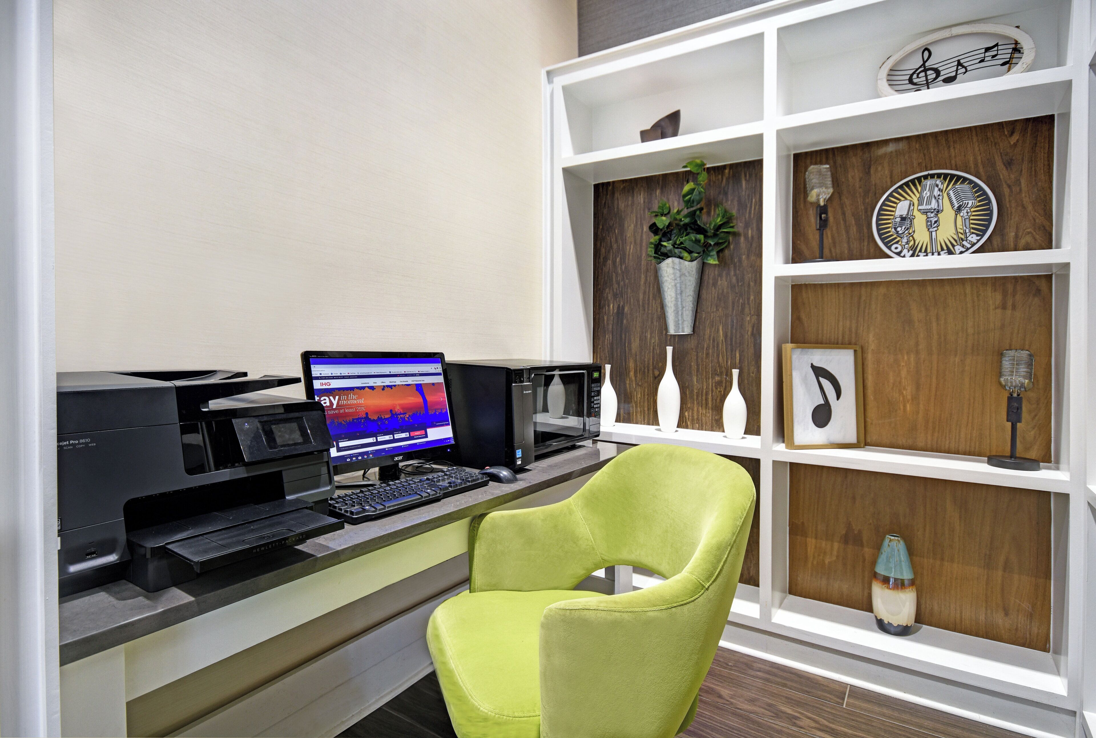 A home office setup with a computer, printer, and a green chair.