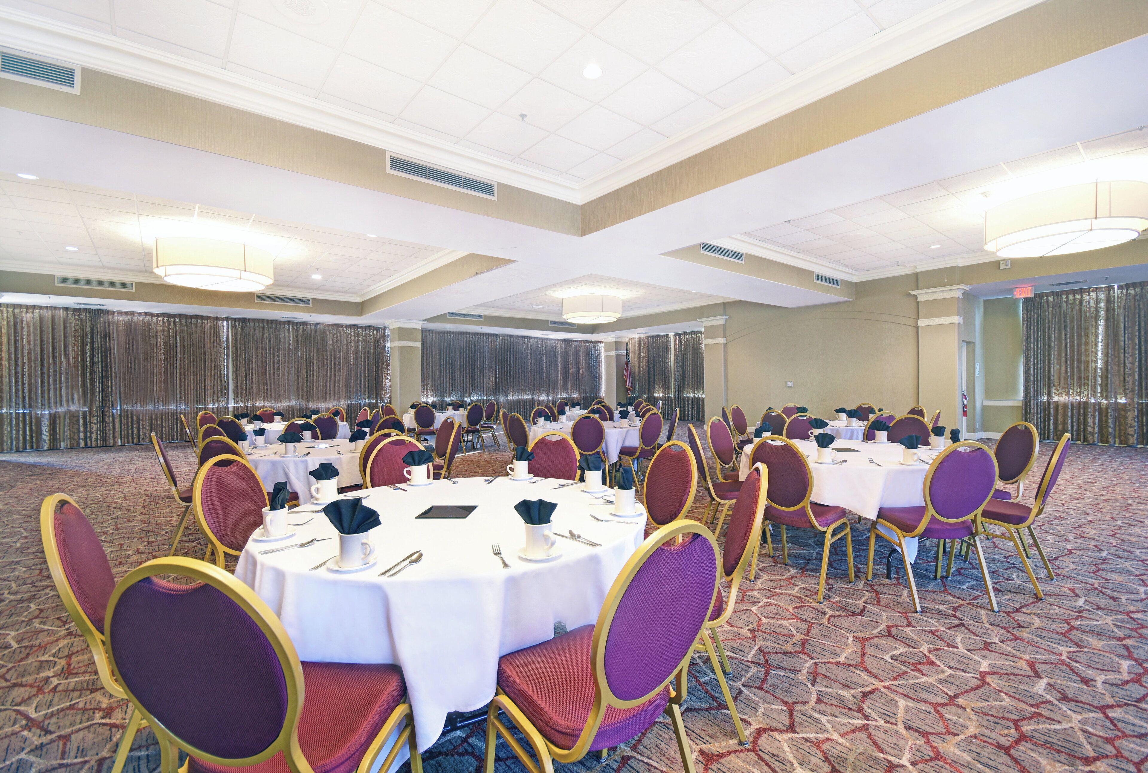 A conference room with round tables, chairs, and a carpeted floor.