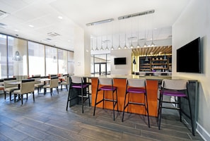 A modern bar area with high stools, a flat-screen TV, and pendant lighting. - Holiday Inn Downtown Memphis by IHG (Memphis)