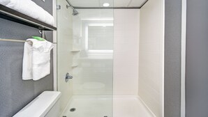 A modern bathroom with a glass-enclosed shower, a white bathtub, and a towel rack with folded towels. - Holiday Inn Downtown Memphis by IHG (Memphis)