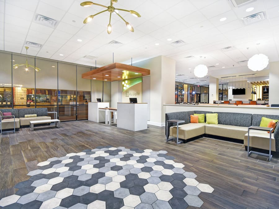 Un vestíbulo moderno con mostrador de recepción, zona de estar y suelo con un diseño hexagonal.
