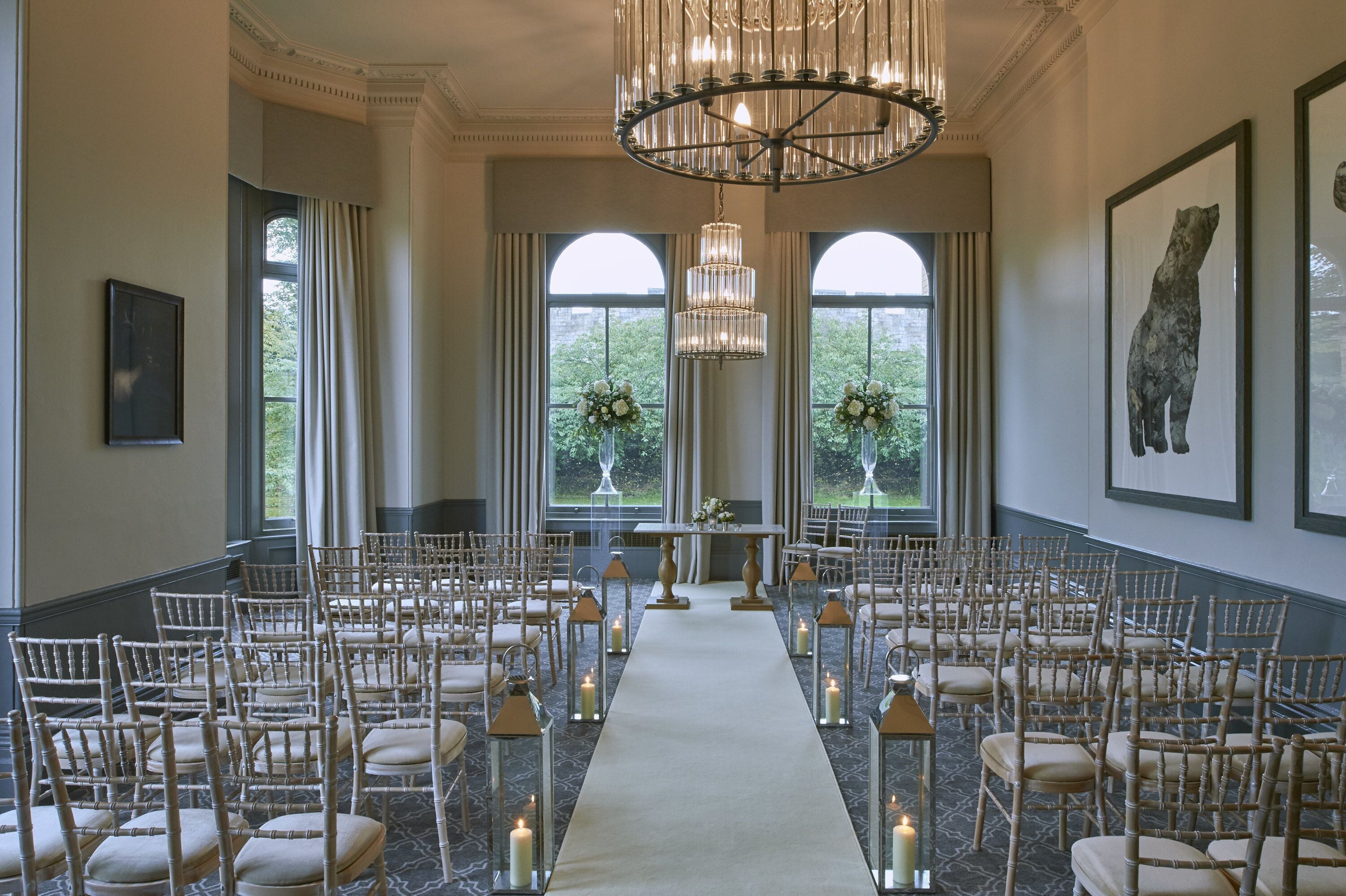 A formal indoor setting with rows of chairs arranged for an event, a central aisle, and a chandelier.