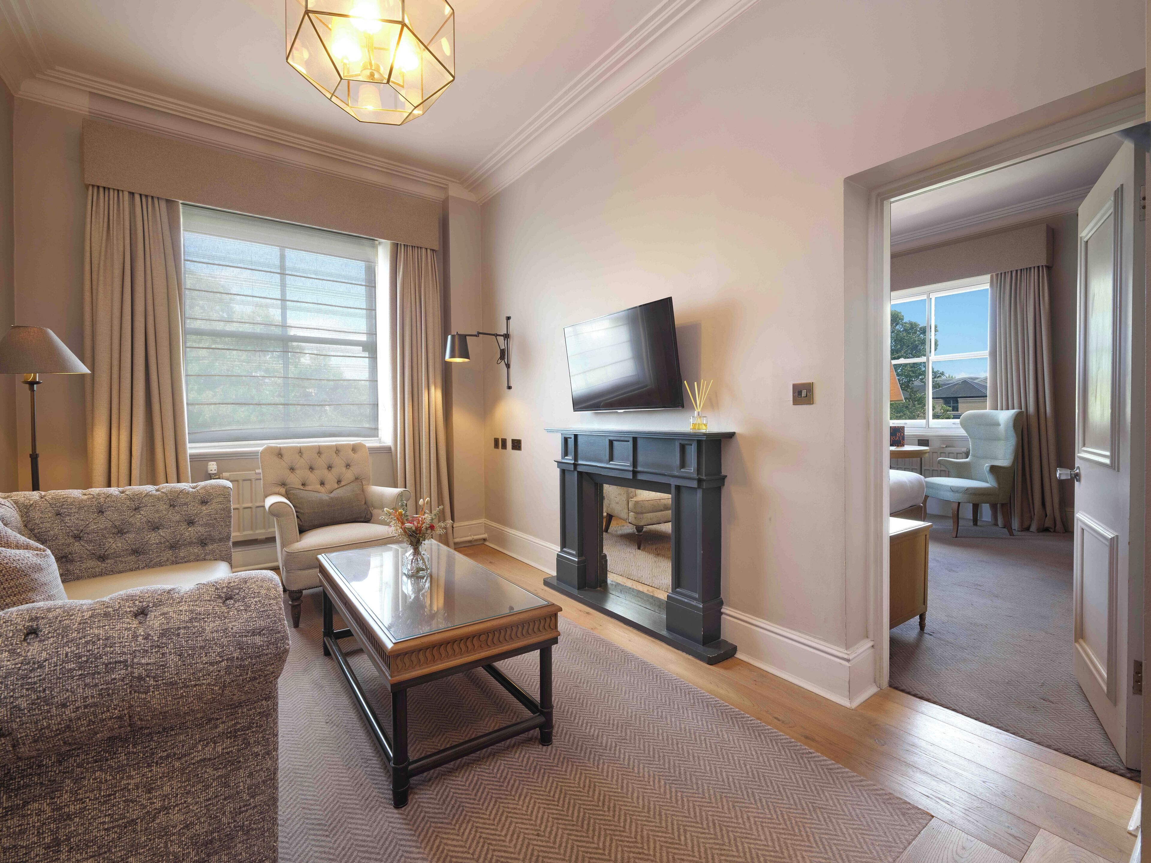 A spacious living room with a large window, a flat-screen TV, a fireplace, and a comfortable seating area.