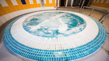 Relax in a hot tub surrounded by a checkered tile wall and mosaic floor.