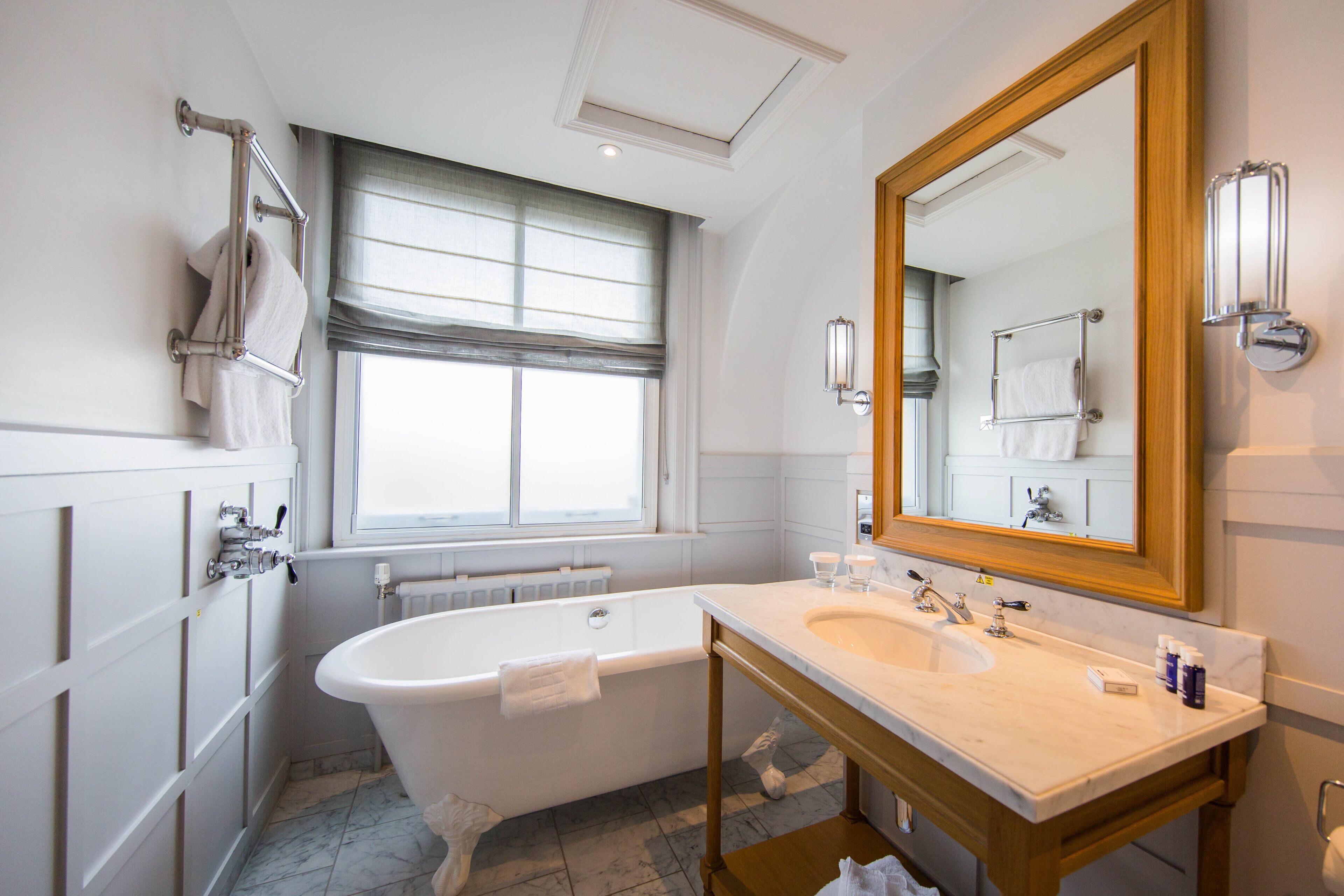 A bathroom with a freestanding bathtub, a large mirror, and a vanity with a sink.