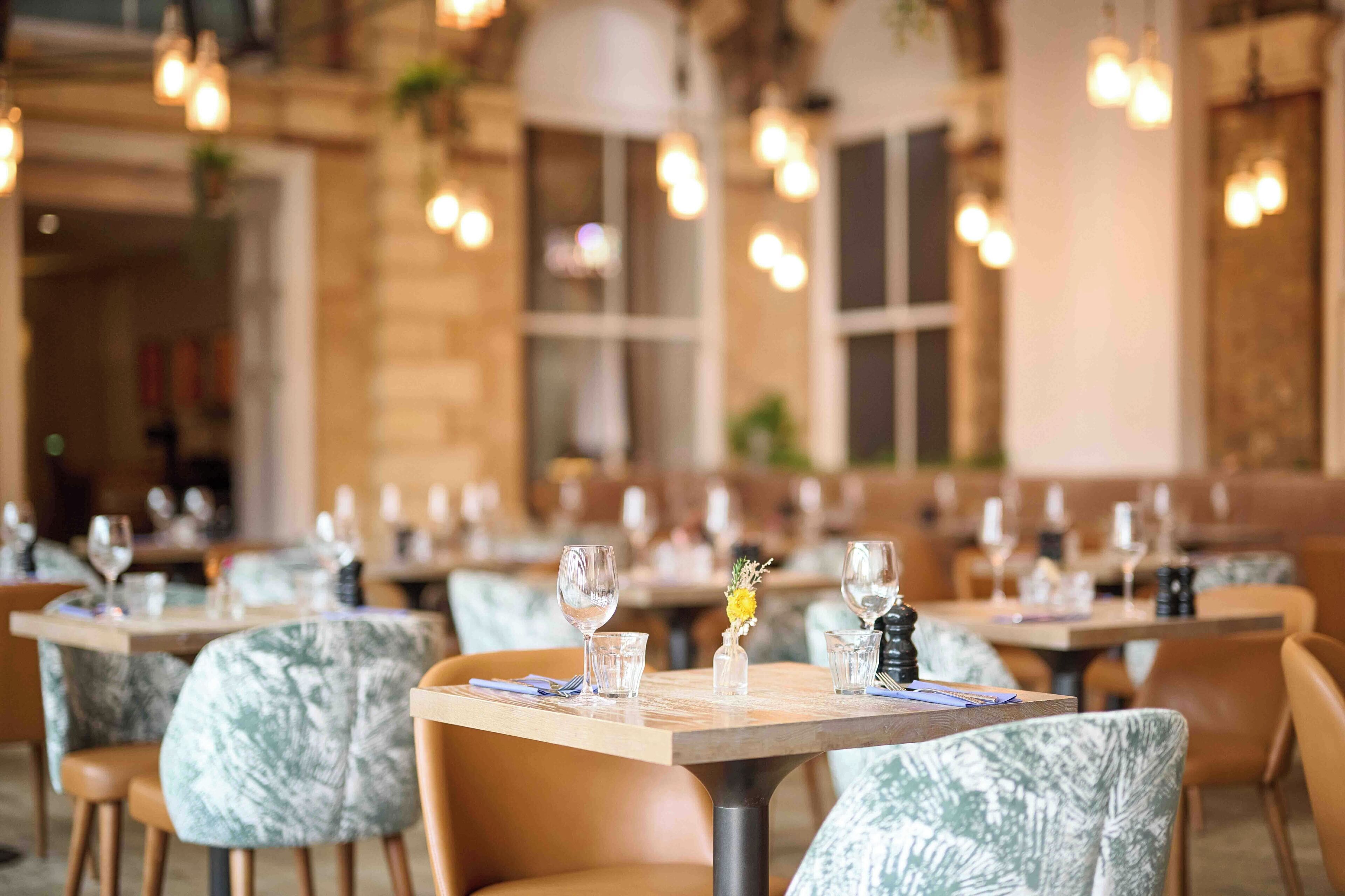 Un restaurante con mesas dispuestas para comer, con una decoración clásica que incluye luces colgantes y un fondo de pared de ladrillo.