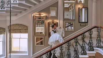 A grand staircase with ornate iron railings and multiple mirrors on the walls.