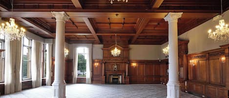 Un salón amplio con techos altos, candelabros ornamentales y ventanas grandes.