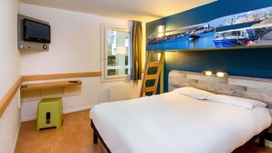 A hotel room with a bed, a TV mounted on the wall, a window, and a wooden floor. - ibis budget Boulogne-sur-Mer Centre les Ports (Boulogne-sur-Mer)