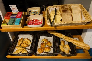 Un bufé de desayuno con pan, bollería y salsas.