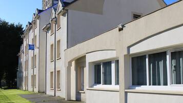 Un bâtiment moderne doté d’un toit plat, de grandes fenêtres et d’une allée pavée.