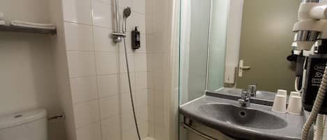 A bathroom with a shower, toilet, sink, and mirror.