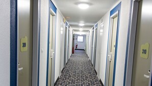 A hotel corridor with doors numbered 309 and 310, carpeted with a geometric pattern, and a ceiling light fixture. - ibis budget Boulogne-sur-Mer Centre les Ports (Boulogne-sur-Mer)