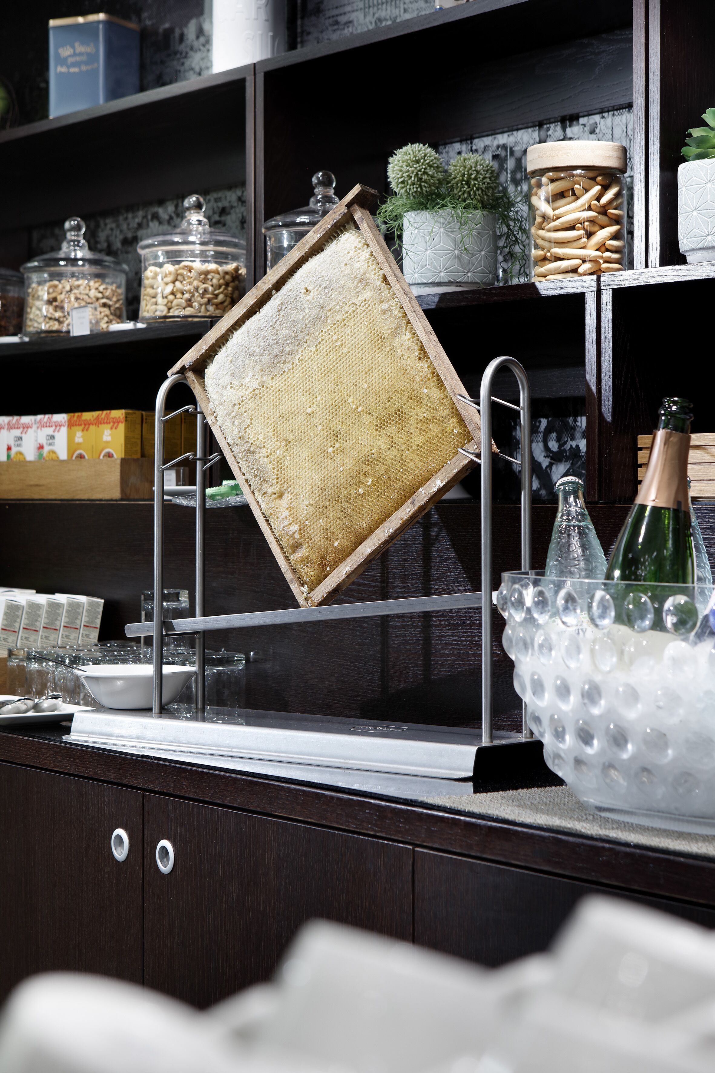 A kitchen counter with a hanging sieve, a glass jar, and a bottle in a bubble container.