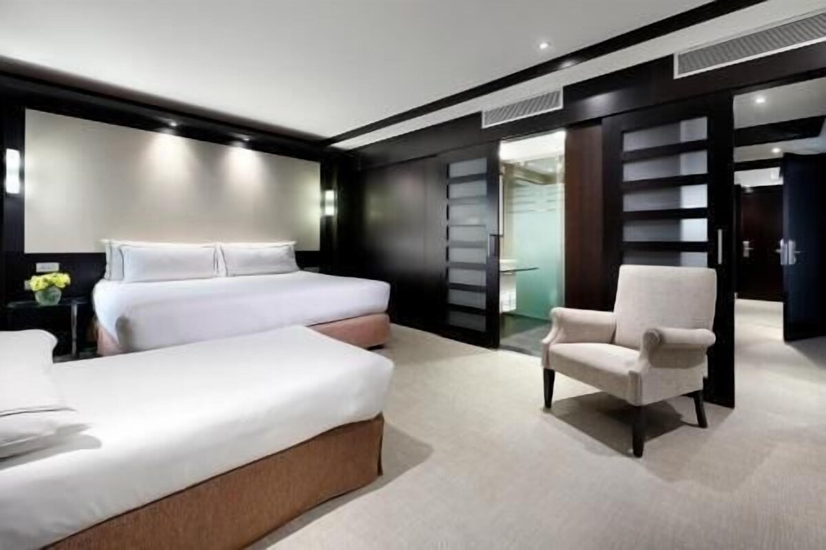 A modern bedroom with a large bed, a chair, and a wardrobe.