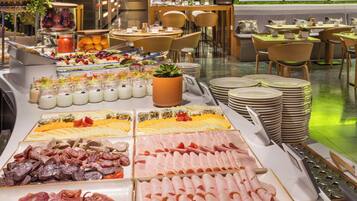 Un bufé con diversas opciones de comida y un área de estar con mesas y sillas.