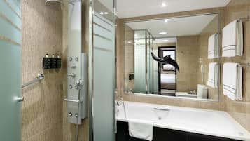 A modern bathroom with a glass shower enclosure, a large mirror, a white sink, and a black bathtub.