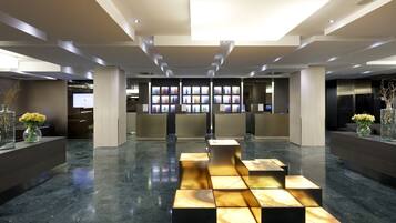 A modern lobby with a central seating area, a reception desk, and a wall of digital displays.