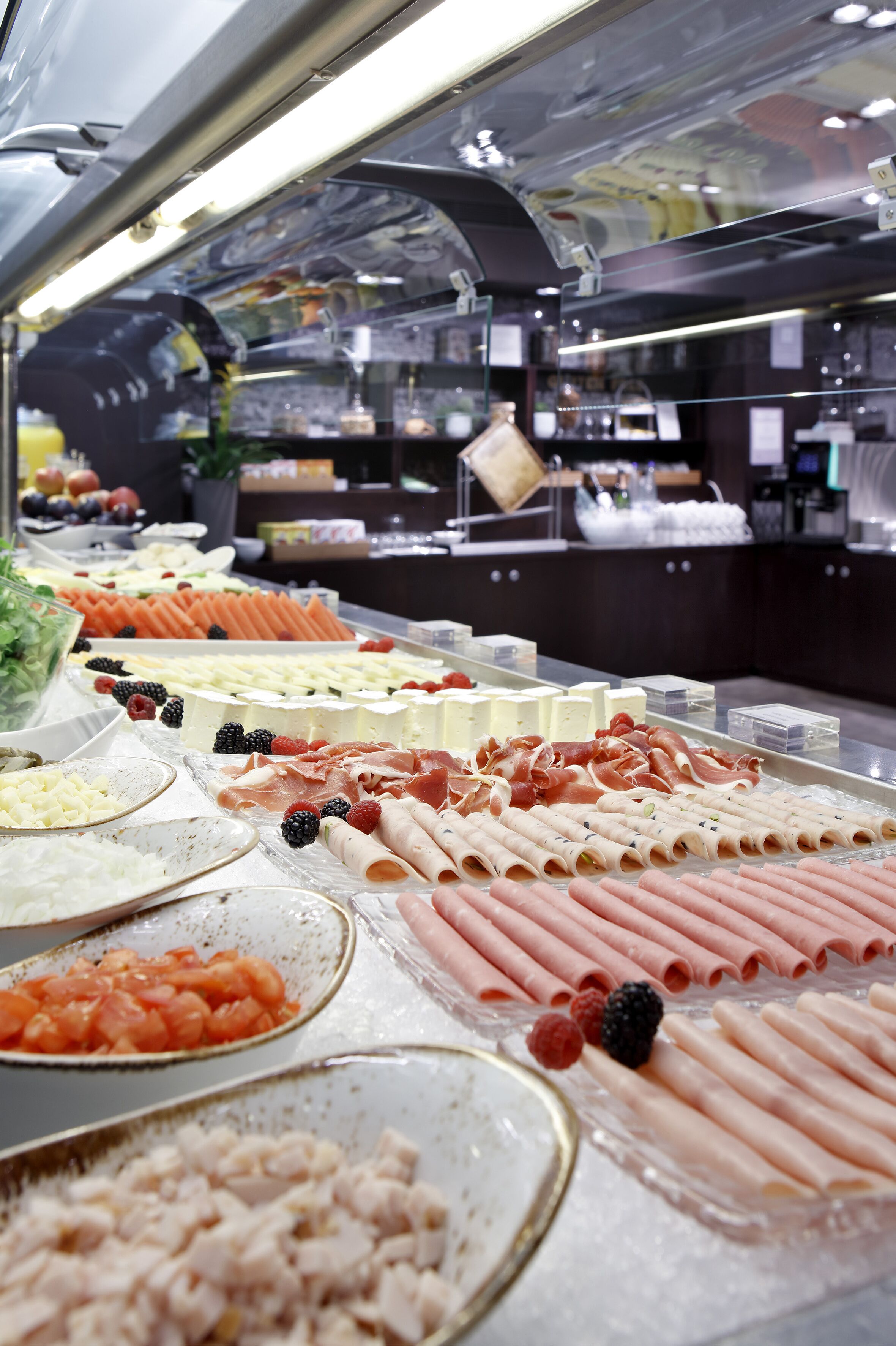 A buffet with various food items including meats, cheeses, and fruits.