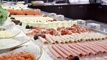 A buffet with various food items including meats, cheeses, and fruits.