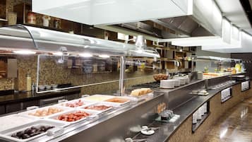 Un bufé con diferentes opciones de comida y una cocina moderna al fondo.