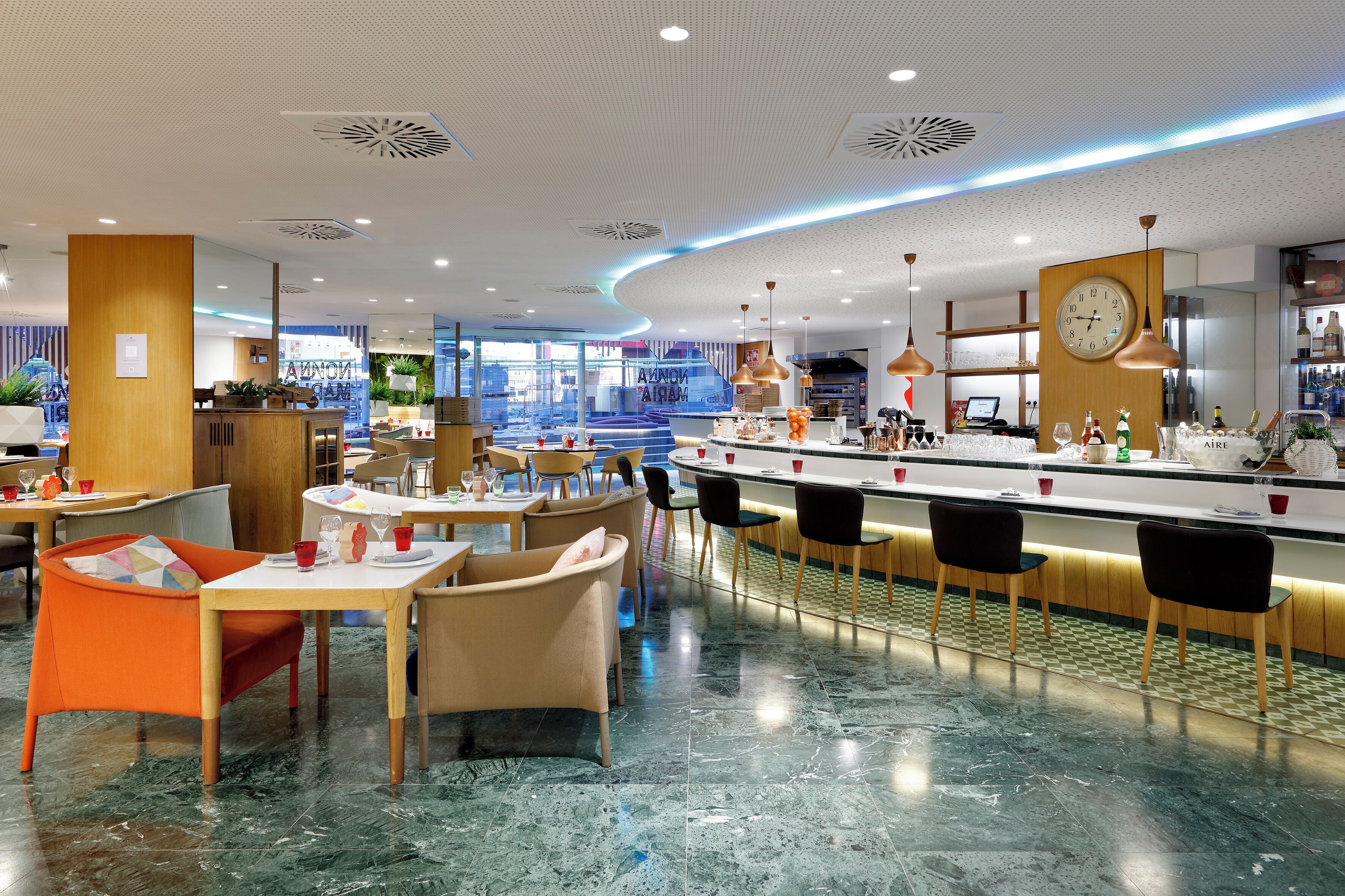 A modern restaurant with a bar area, marble flooring, and contemporary furniture.