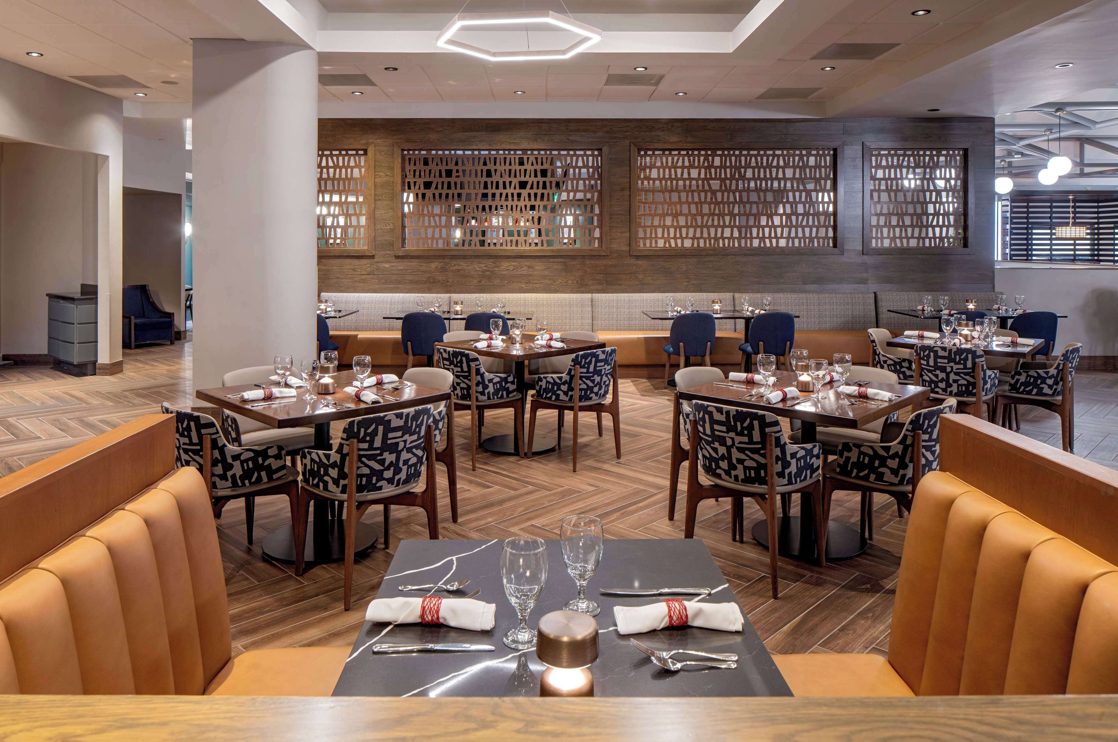 A restaurant with multiple dining tables, chairs, and a wooden floor.