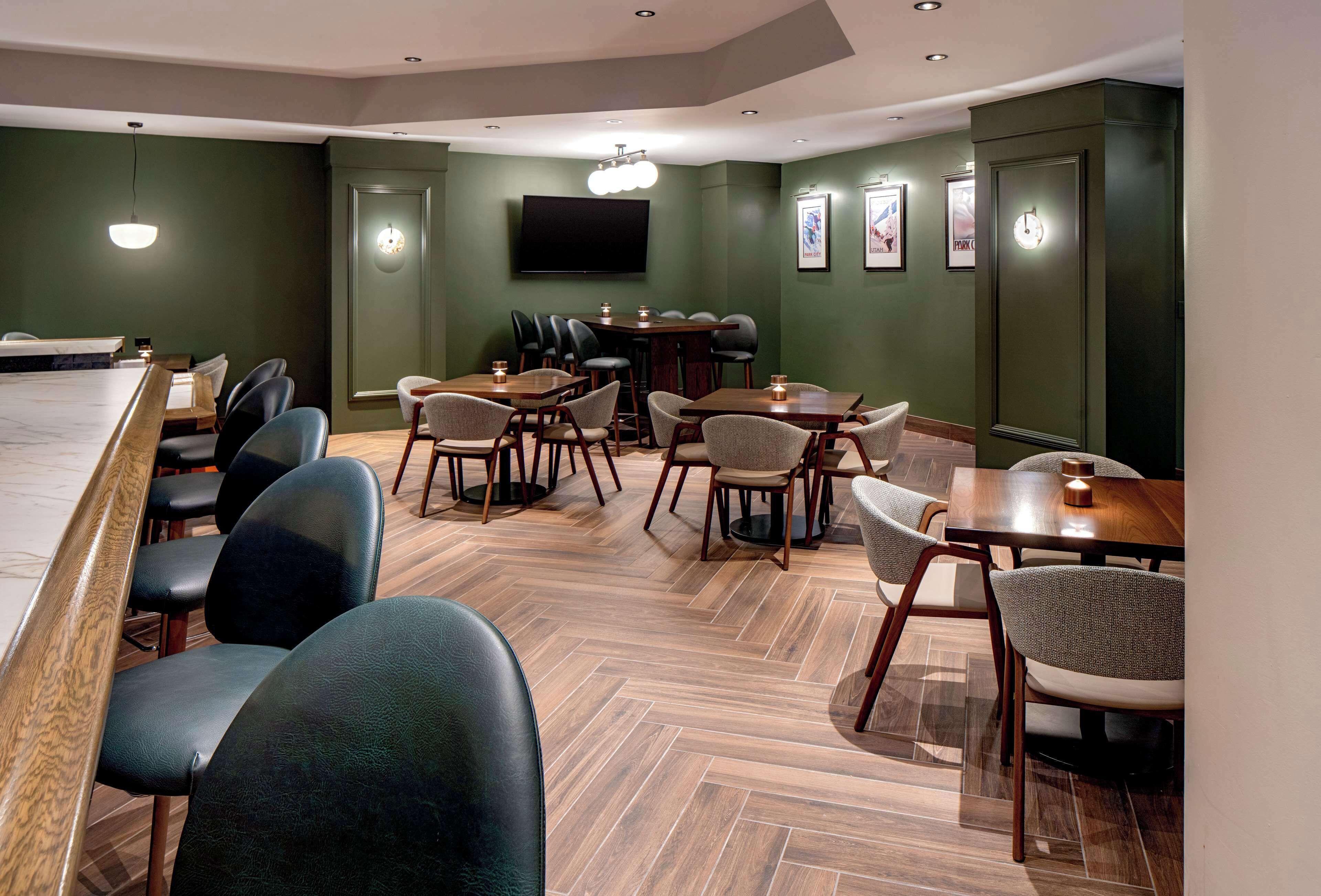 A modern dining area with a long table, multiple chairs, and a bar area.