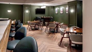 A modern dining area with a long table, multiple chairs, and a bar area.