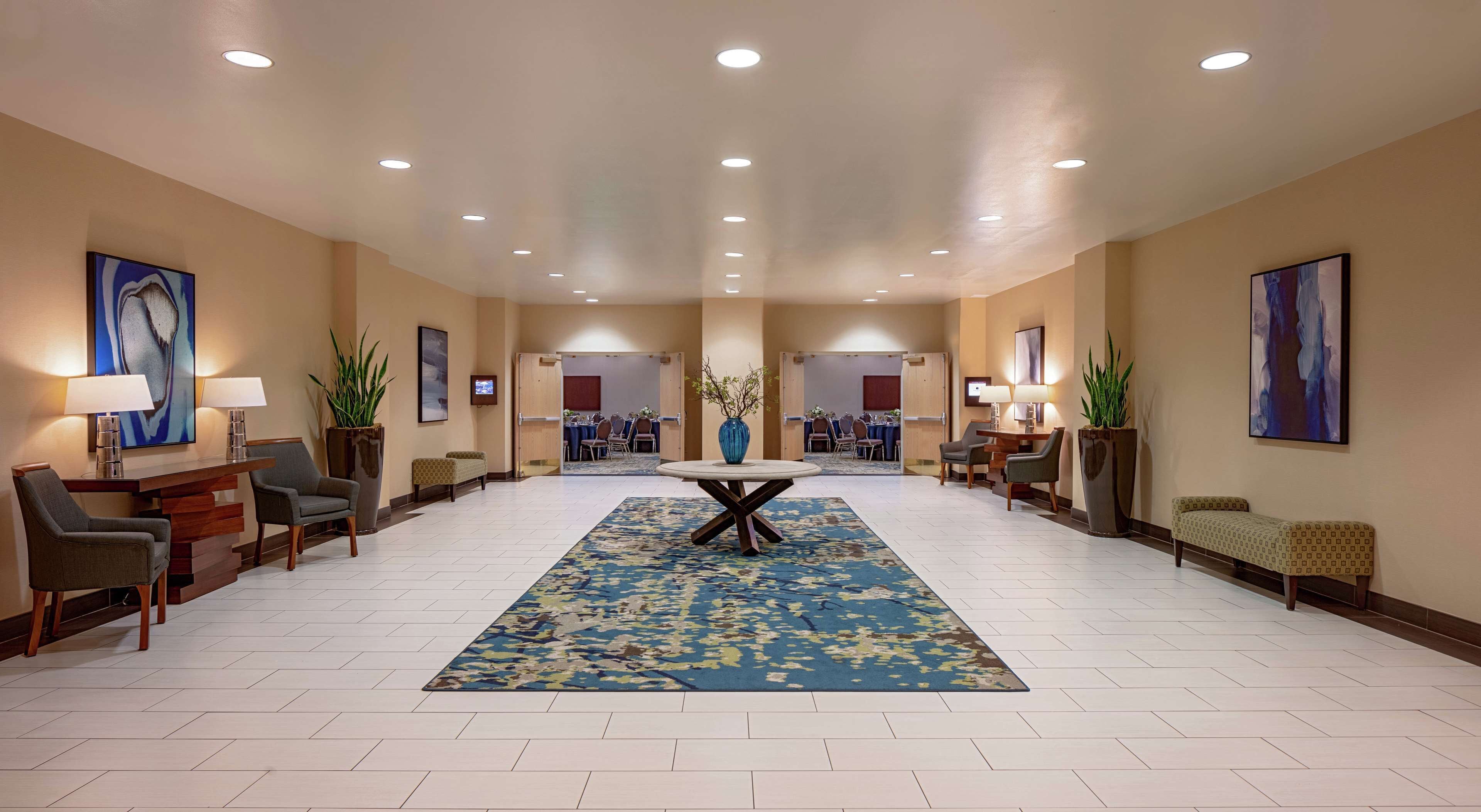 Un hall d’entrée spacieux avec une table ronde centrale, plusieurs coins salon et des œuvres d’art accrochées aux murs.