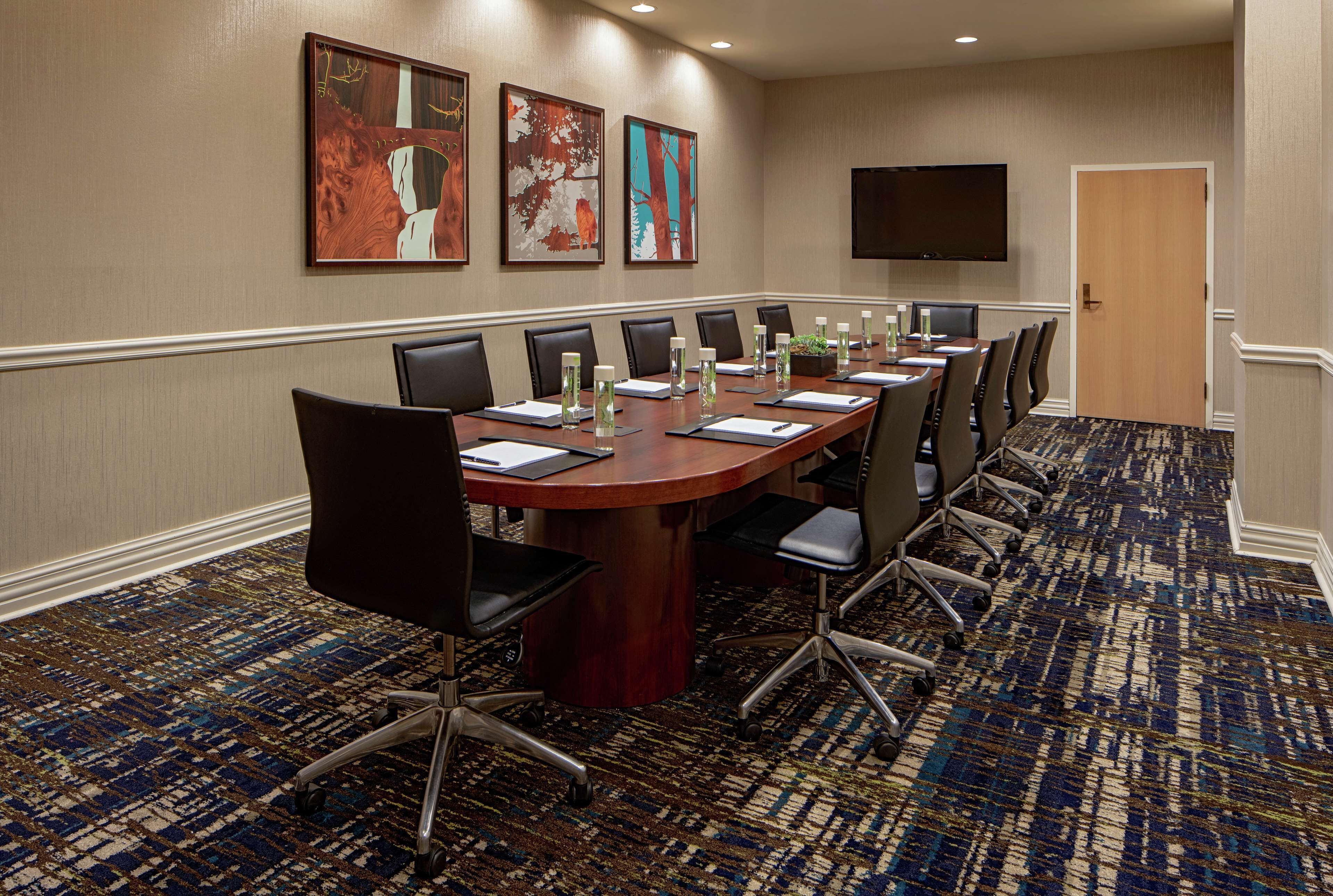 A conference room with a long table, chairs, and a flat-screen TV on the wall.