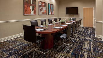 A conference room with a long table, chairs, and a flat-screen TV on the wall.