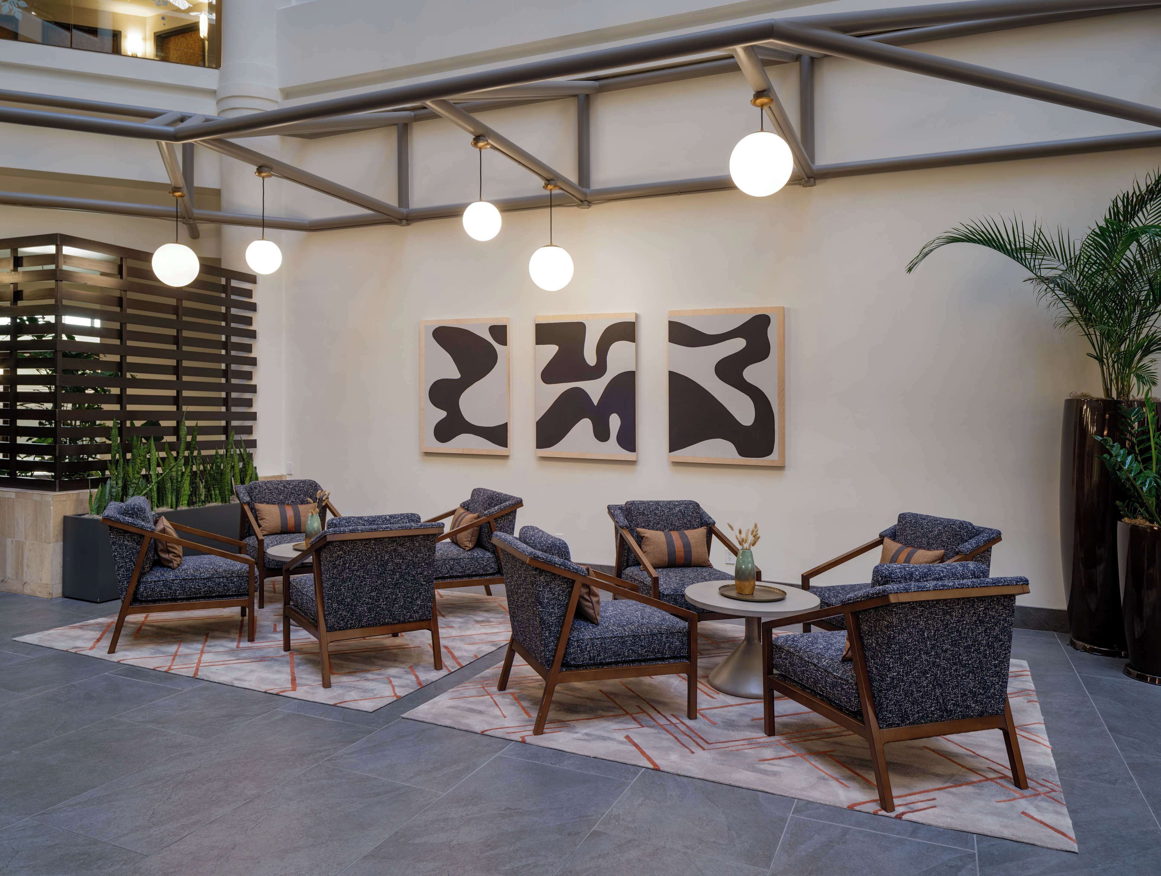 A lobby with modern furniture, abstract wall art, and a large potted plant.
