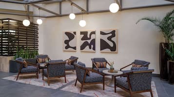 Un vestíbulo con muebles modernos, arte abstracto en las paredes y una planta grande en maceta.