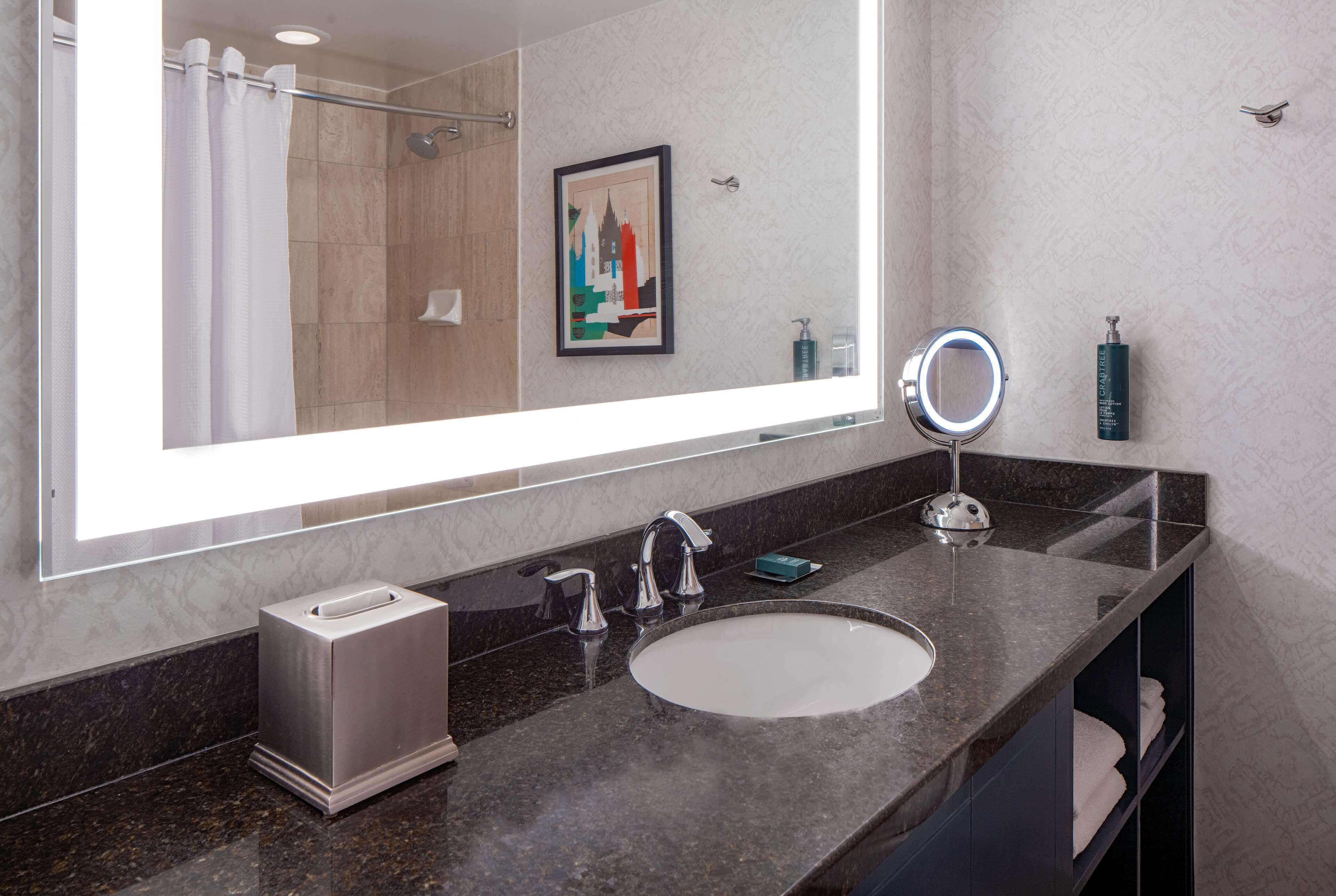 A modern bathroom with a large mirror, a sink, and a shower.