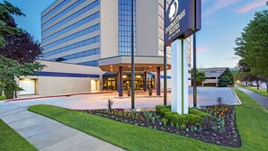 A modern hotel building with a prominent entrance, a well-maintained garden, and the DoubleTree by Hilton logo. - DoubleTree Suites by Hilton Hotel Salt Lake City (Salt Lake City)