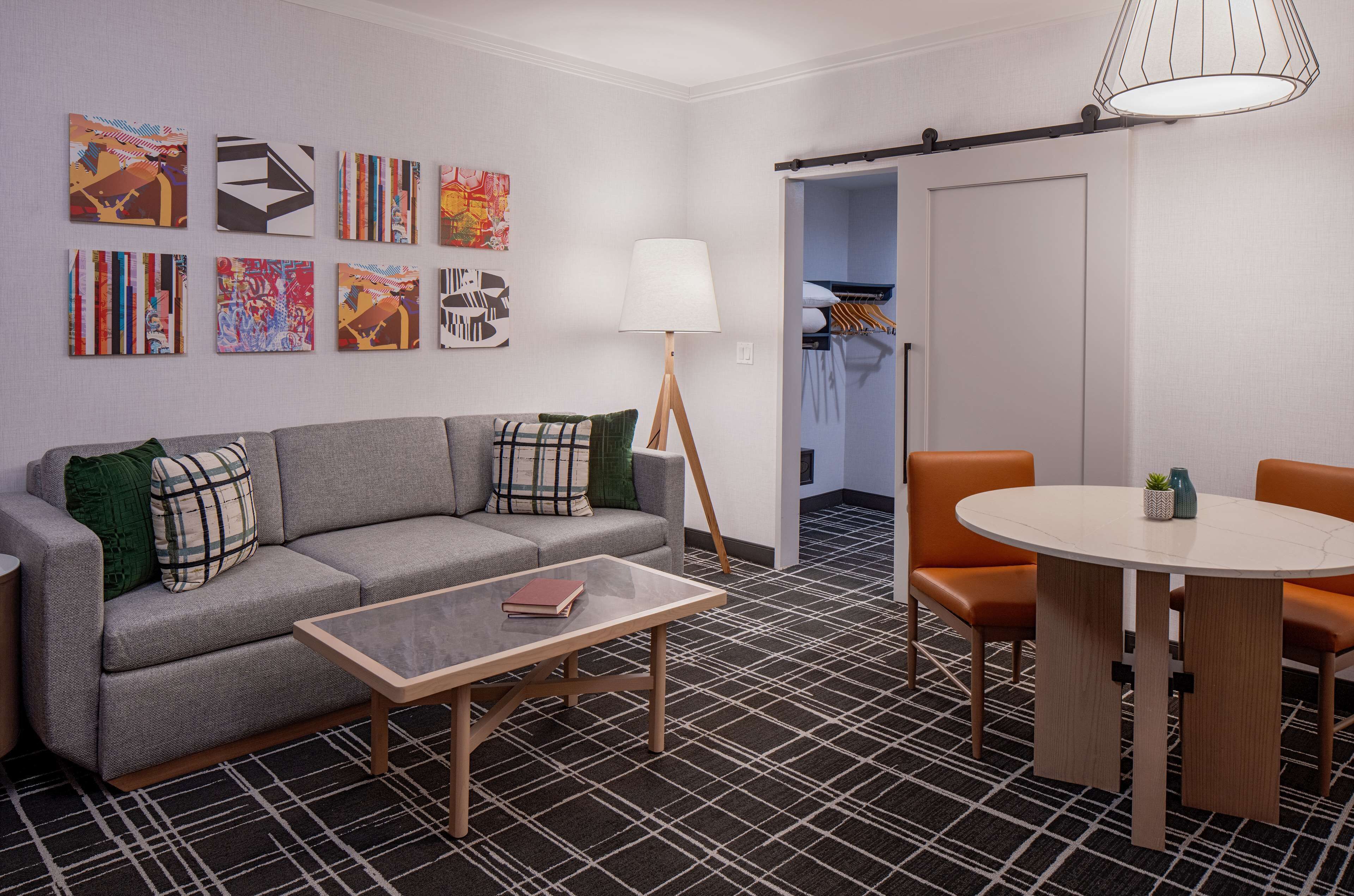 A modern living room with a sofa, coffee table, and a dining area with a table and chairs.
