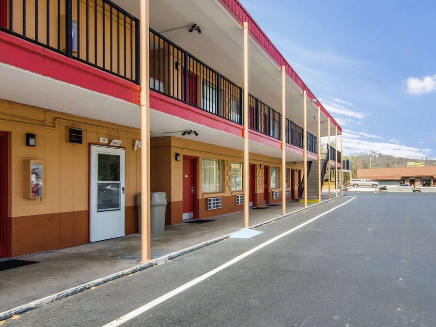 A motel with multiple rooms, a covered parking area, and a small building in the background.