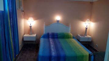 A room with a bed, two bedside tables, and a nightstand.