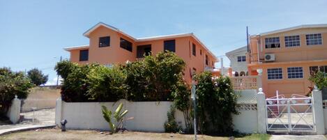 A two-story building with a flat roof and a white fence in front.