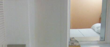 A room with a walk-in closet, a desk with a chair, and a bed.