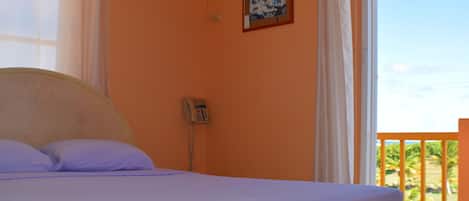 Une chambre avec un lit, un téléphone et un tableau au mur.