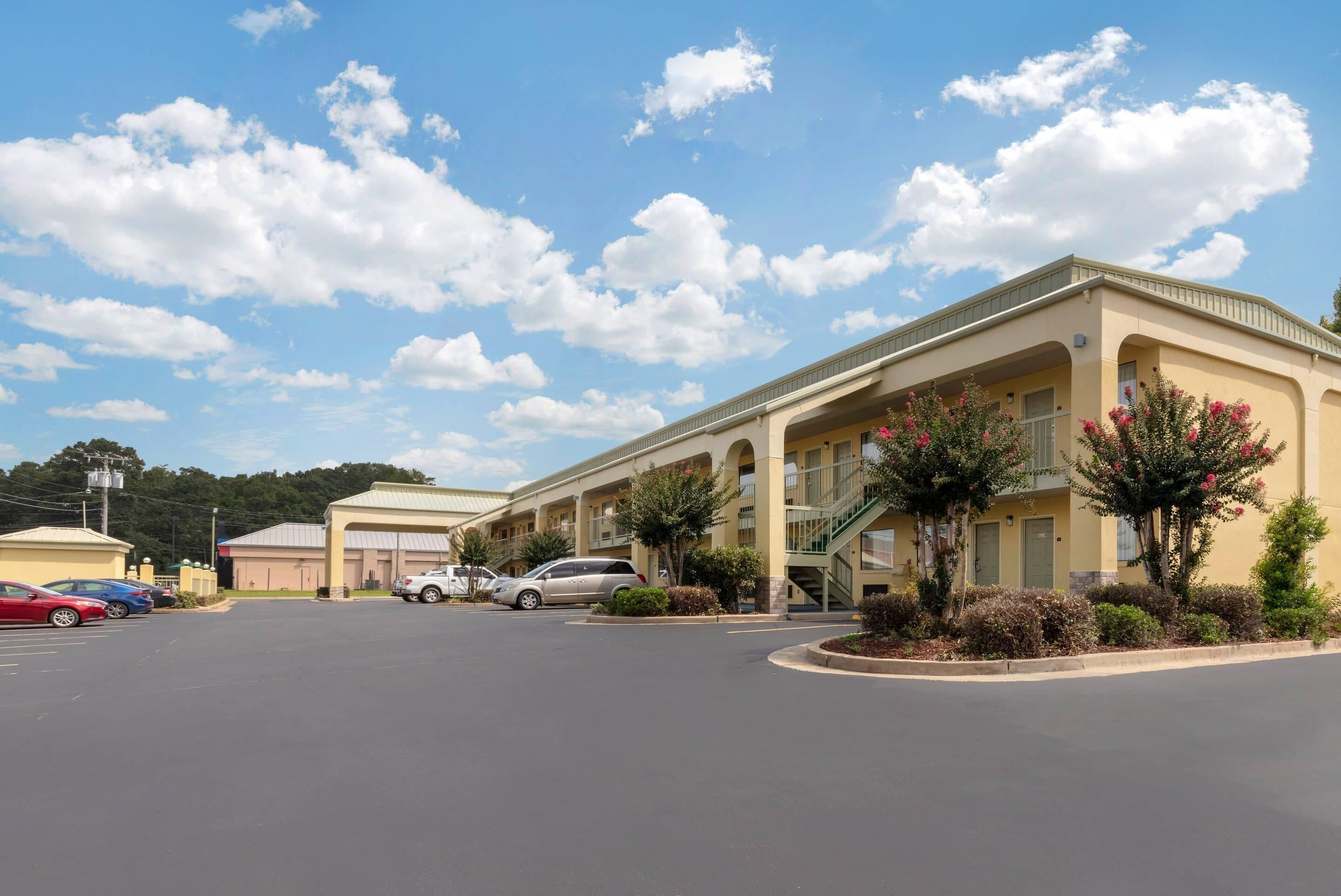 A hotel with a parking lot, multiple buildings, and a clear sky.