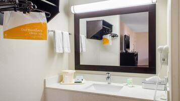 Casa de banho de hotel com um espelho grande, uma pia, um telefone e um porta-toalhas.