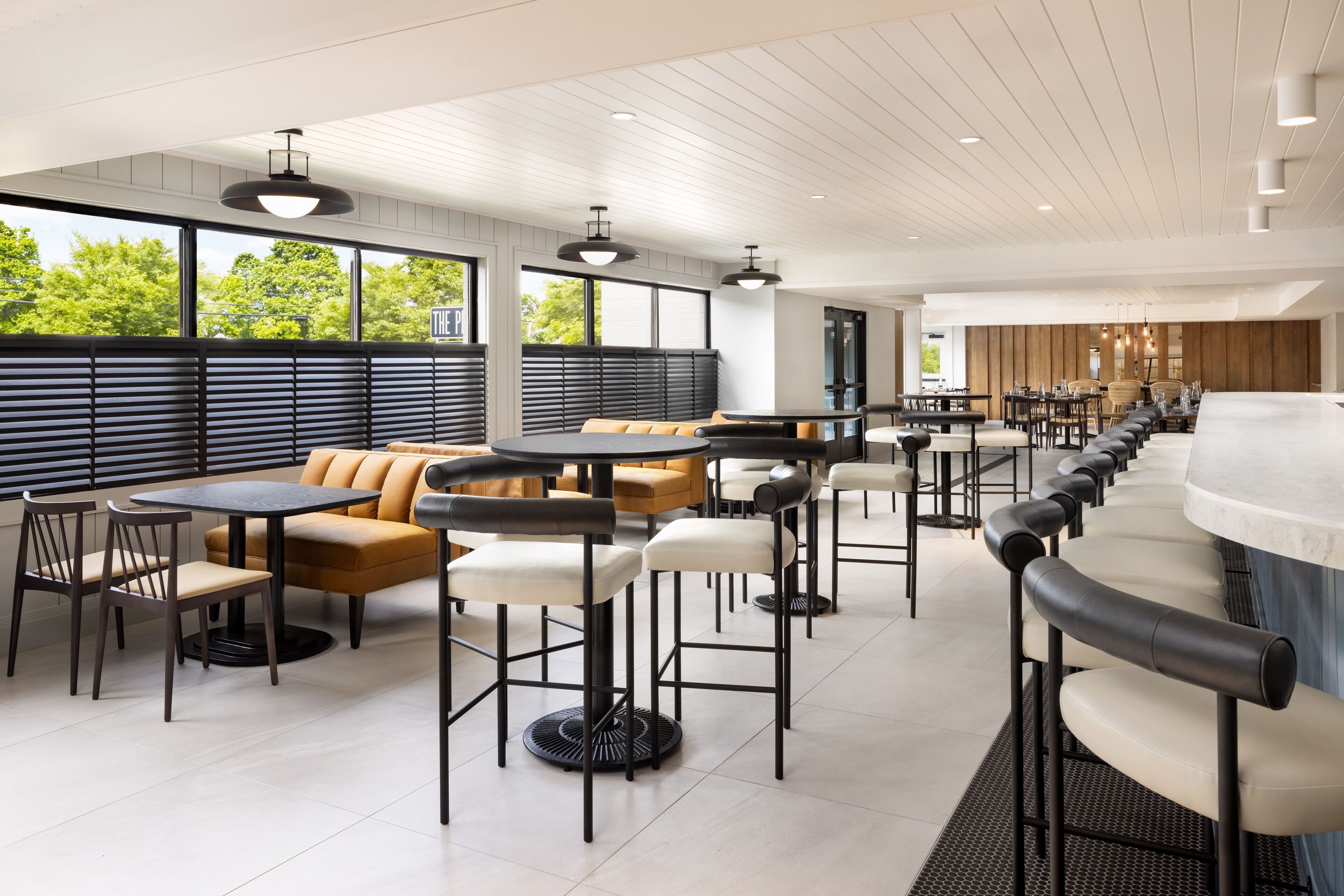 A modern restaurant with high ceilings, large windows, and a variety of seating options including tables and booths.