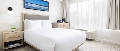 A neatly arranged hotel room with a bed, bedside table, and a window with curtains.