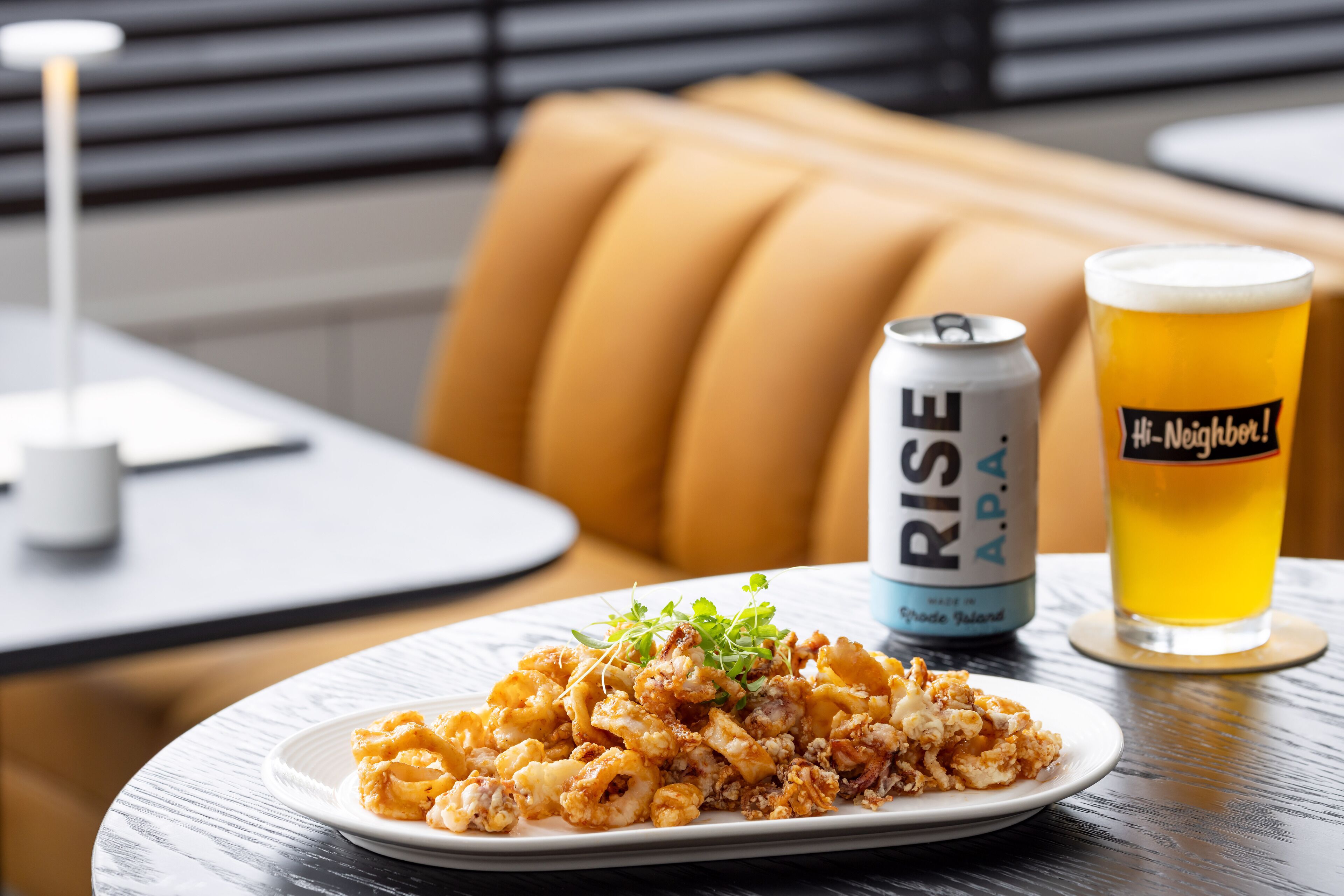 Une assiette de nourriture, une canette de bière et un verre de bière sur une table.
